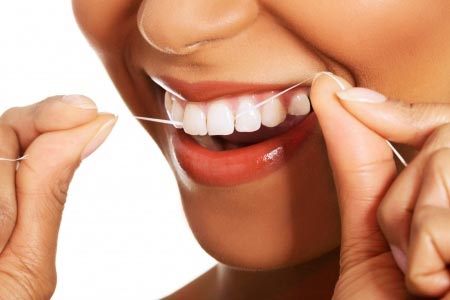 Person flossing between teeth to care for their gums