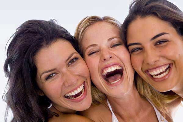 Three adults smiling in a restorative dentistry image from the practice website